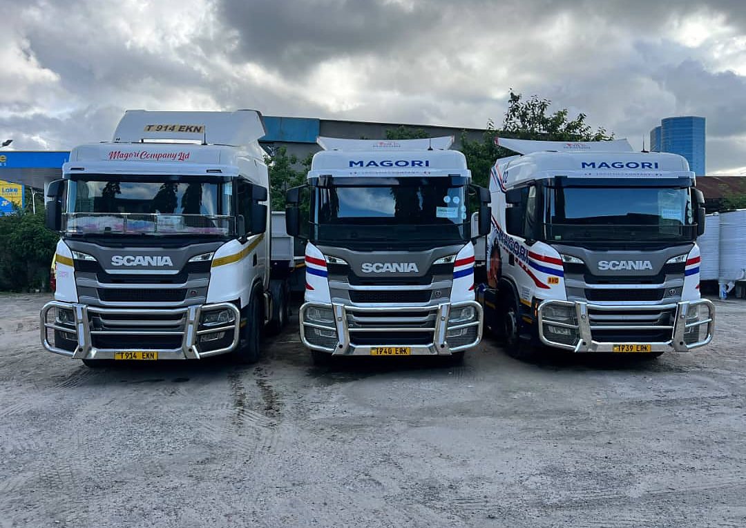 Three Magori Logistics trucks head-on under a stormy sky