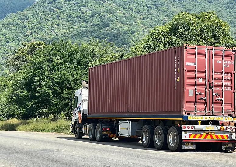 A Magori Logistics truck carrying a container on the road through the hills