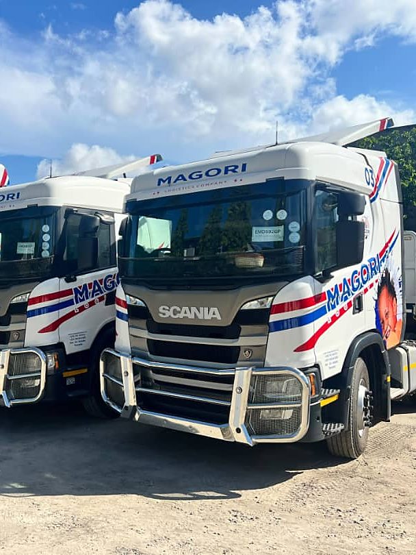 Three Magori Logistics trucks parked in a row