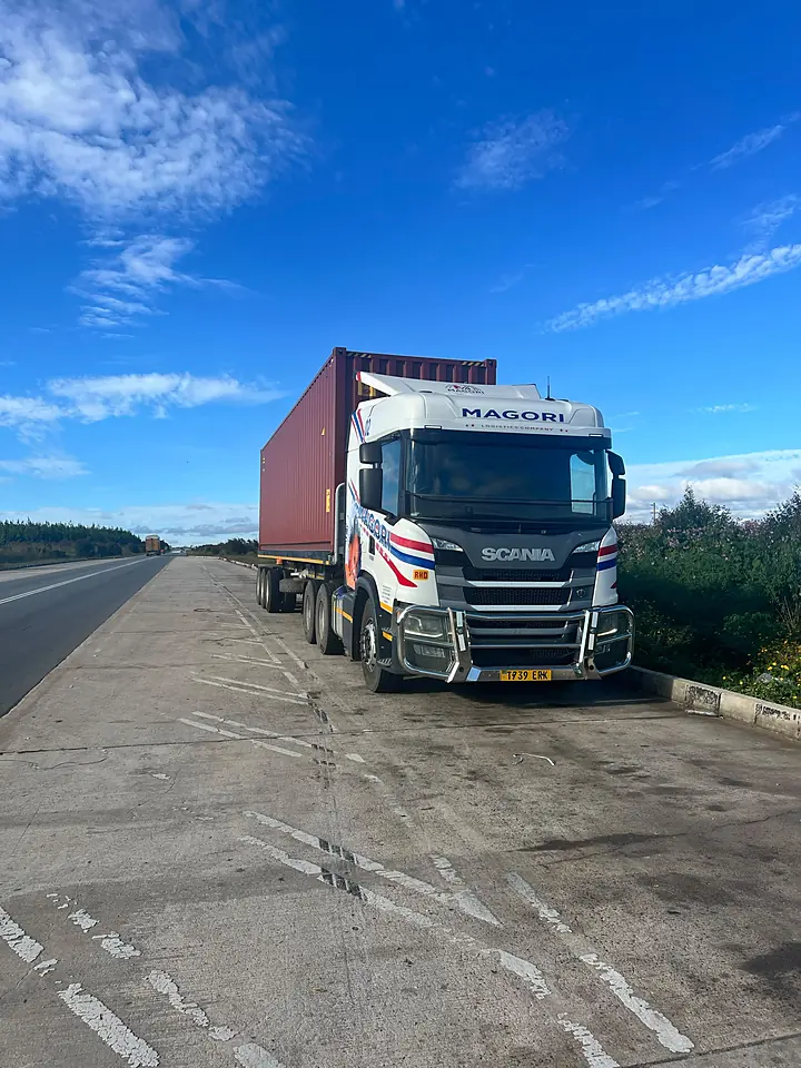 A Magori Logistics truck with a loaded container under a blue sky