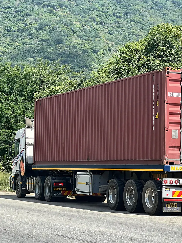 A Magori Logistics truck carrying a container on an upcountry road